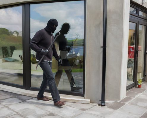 Burglar with wrecking bar preparing to enter a property through a glass door or window
